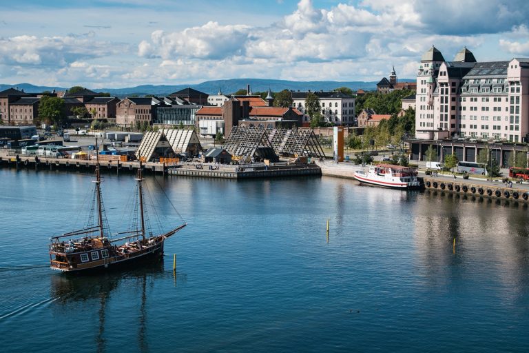 Seilskute og gamle bygninger ved sjøen nedenfor Akershus festning i Oslo