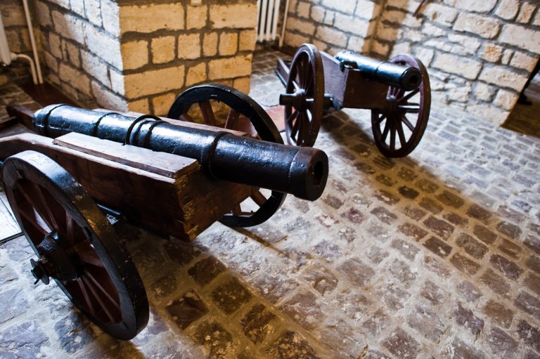 To gamle jernkanoner på hjullavetter utstilt på brosteinsgulvet i et museum