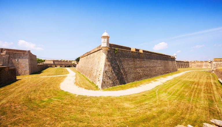 Lave festningsmurer og en bastion av stein under blå himmel